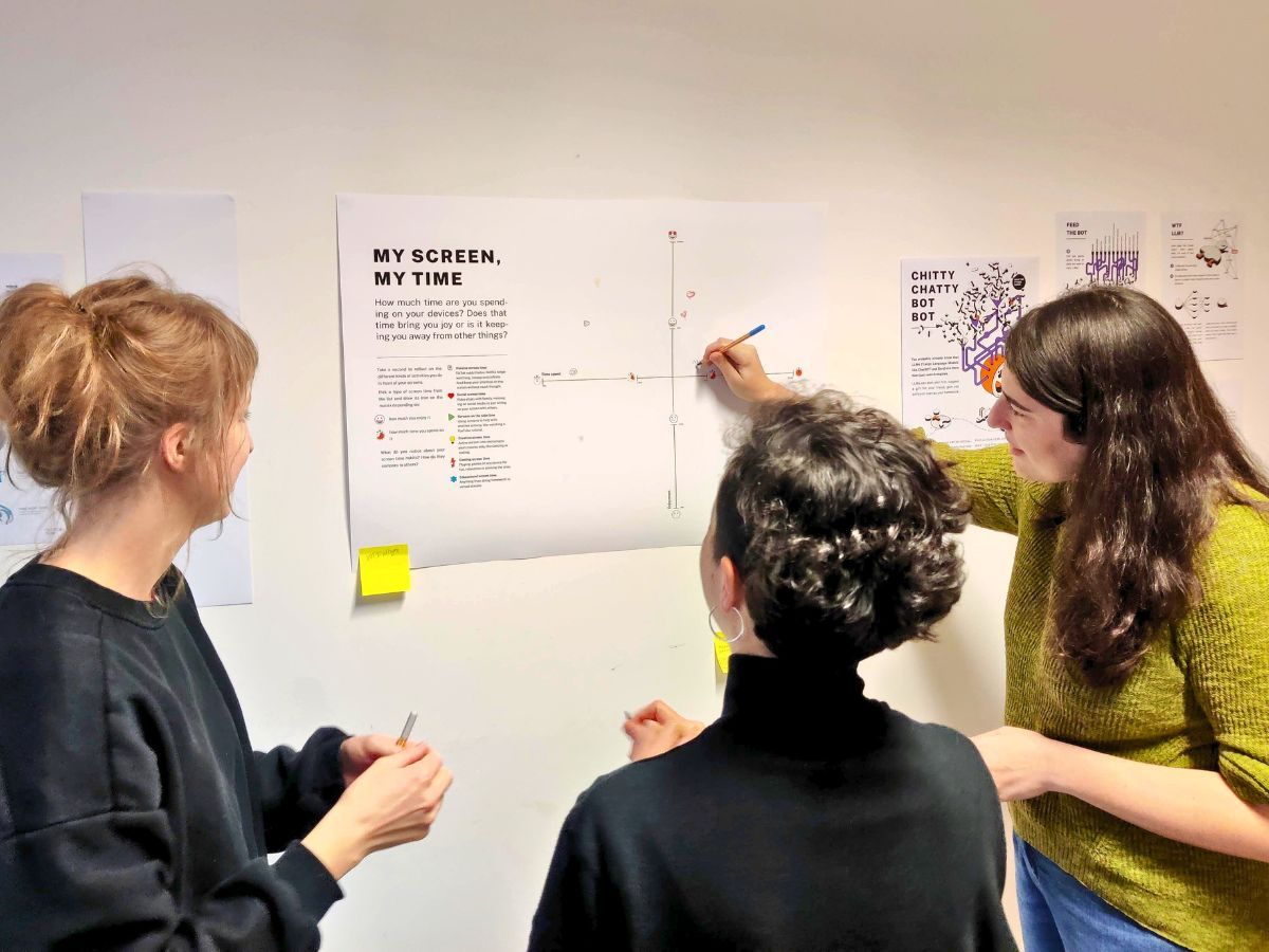 3 persons in front of a colourful poster collaborating